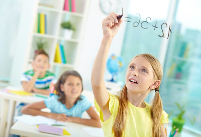 Fille écrivant des mathématiques au tableau.