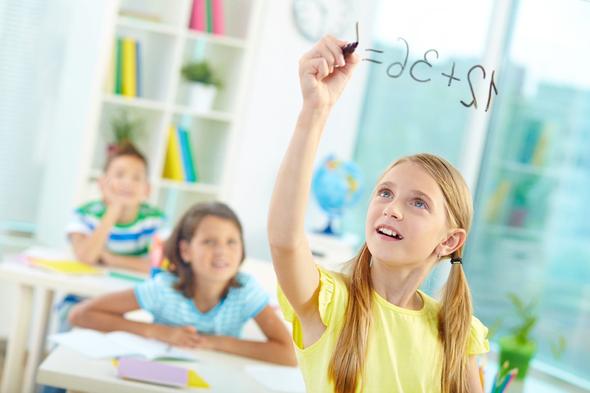 Fille écrivant des mathématiques au tableau.