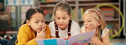 Trois filles lisent un livre.